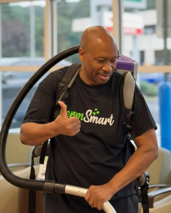 GermSmart cleaner wearing a backpack vacuum and giving a thumbs-up