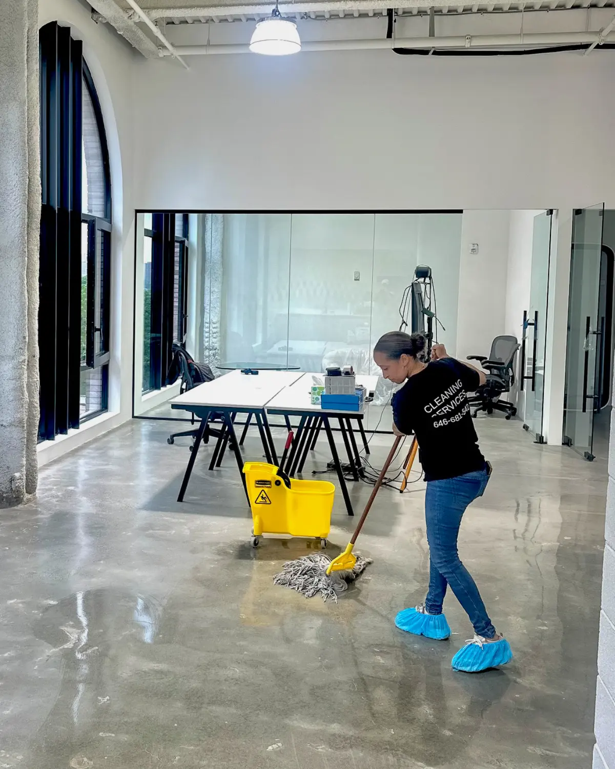 Cleaner mopping a polished floor in a bright modern facility